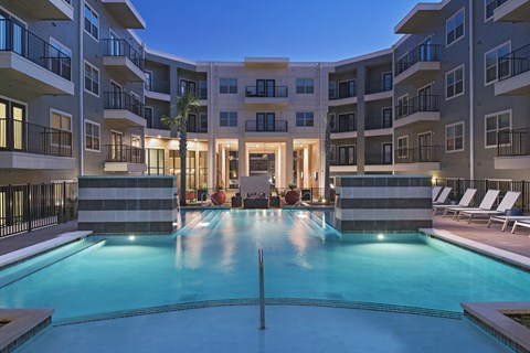 A large swimming pool in front of a building with a balcony.