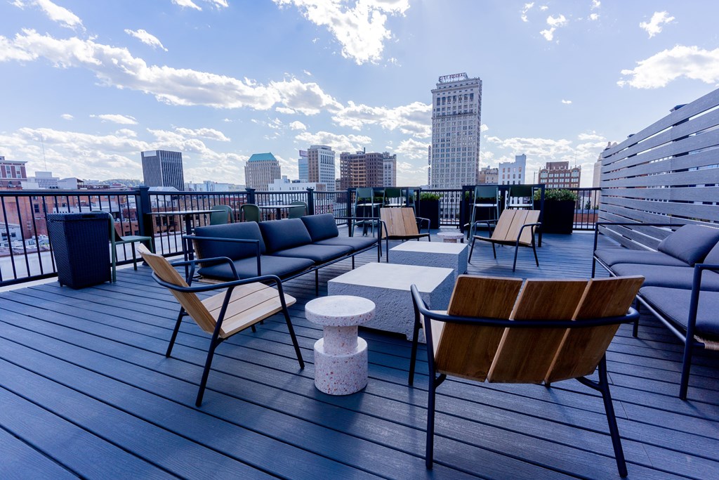 A wooden chair is on a wooden deck with a city skyline in the background.