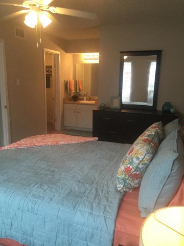 the bedroom has a large bed and a bathroom with a sink