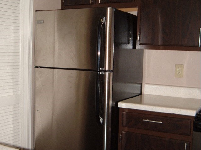 a stainless steel refrigerator in the corner of a kitchen