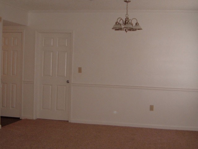 an empty living room with a door and a chandelier
