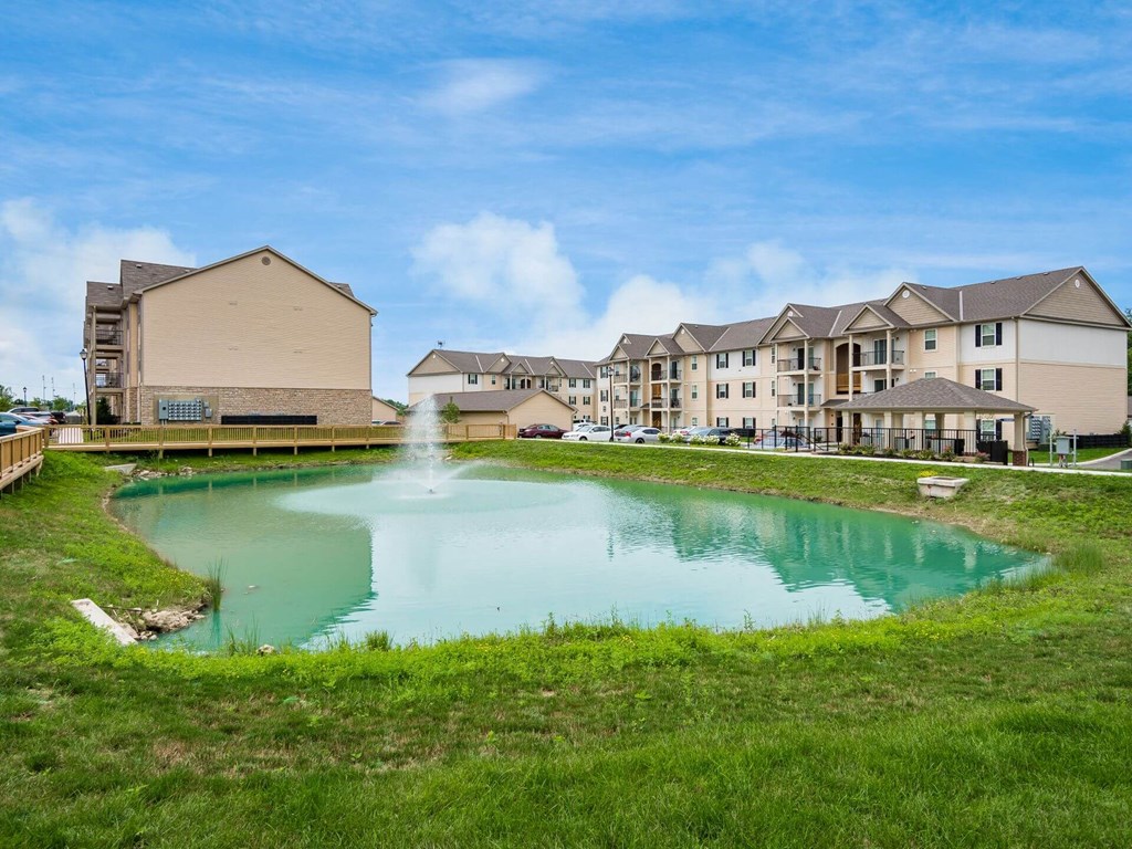 a pond with a fountain in front of an apartment building