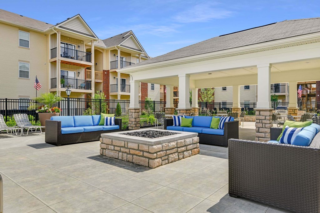 a patio with couches and a fire pit in front of an apartment building