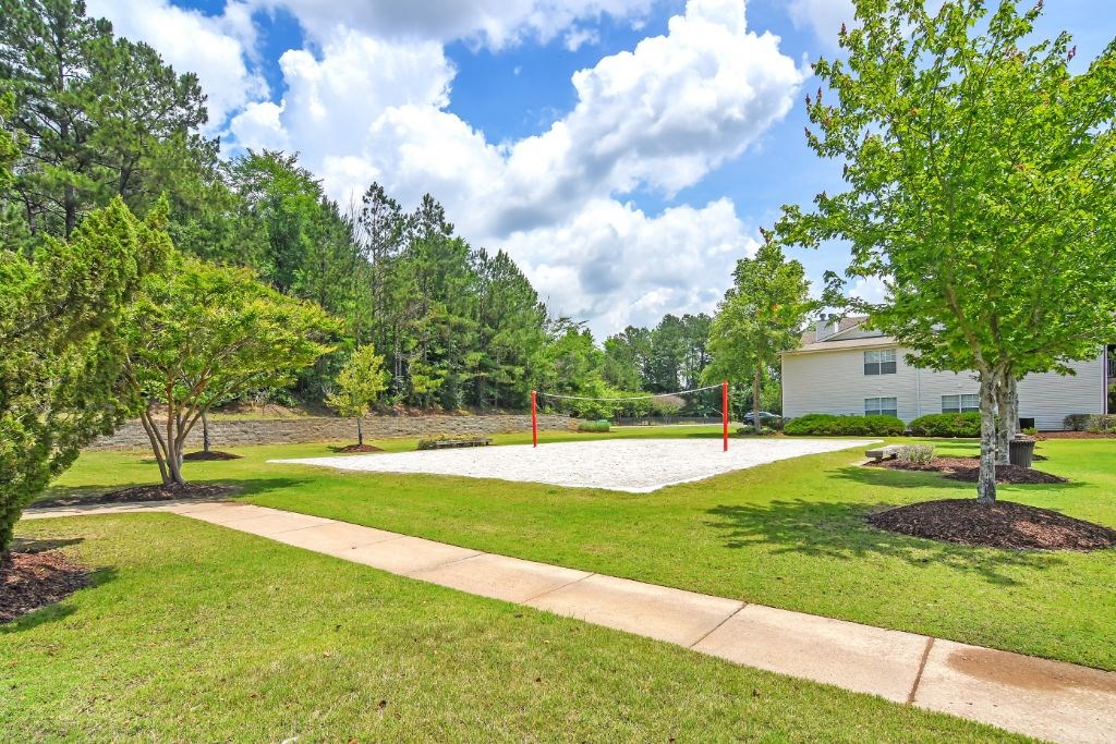 a park with a volleyball court and house in the background