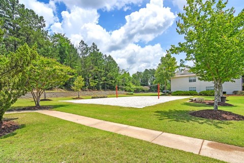 a park with a volleyball court and house in the background