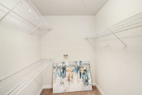 a bedroom with white walls and a large painting on the floor