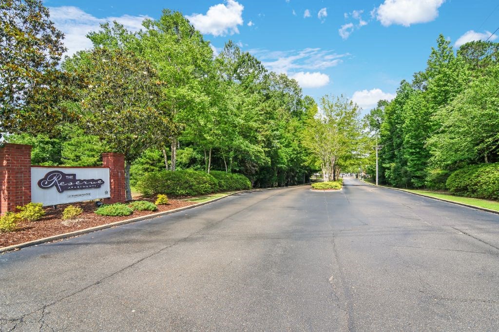 a street with a sign and trees on both sides of the street