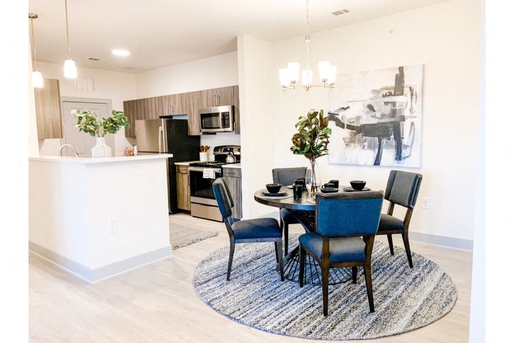 a dining area with a table and chairs and a kitchen in the background