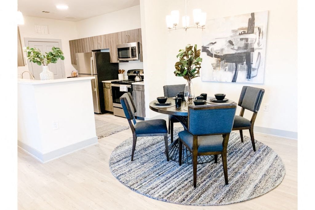 a dining area with a table and chairs and a kitchen in the background