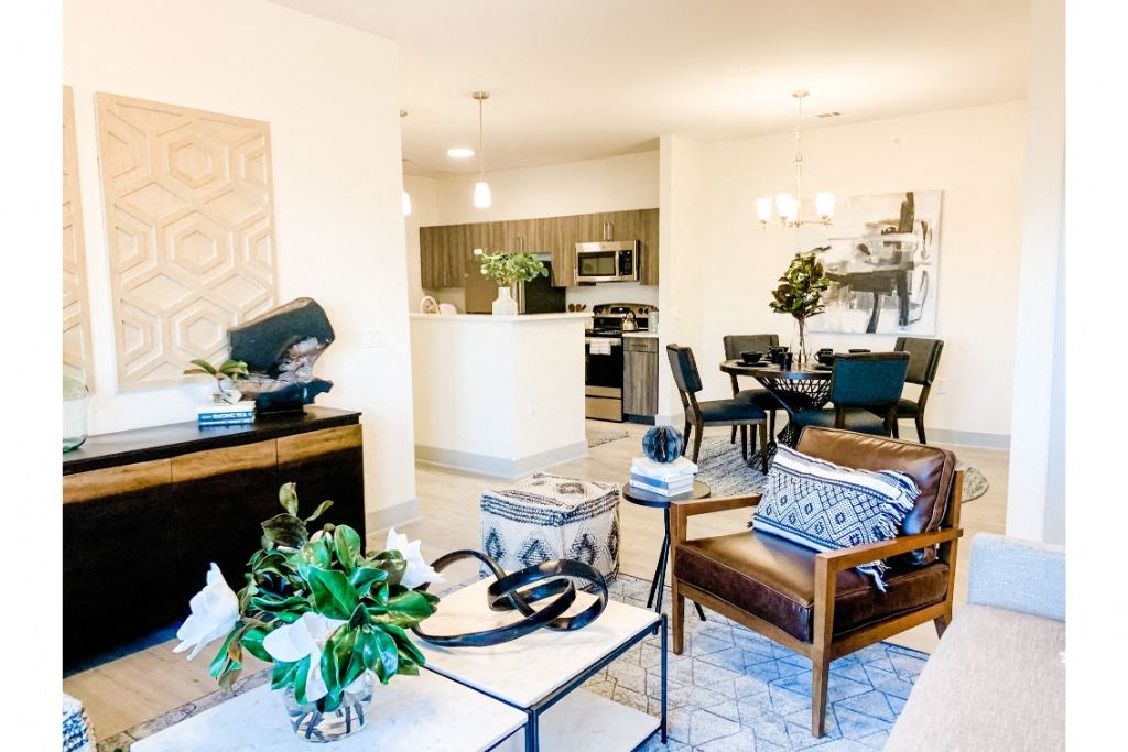 a living room with a couch and chairs and a kitchen in the background