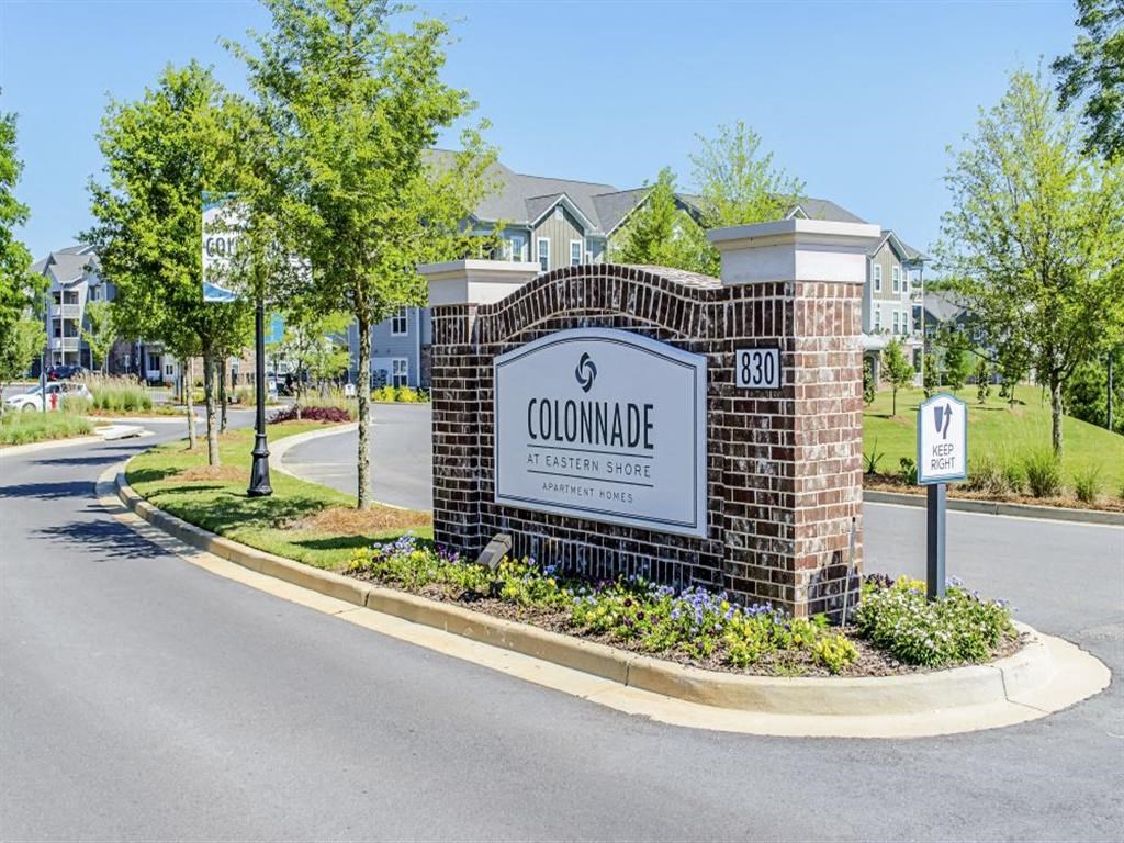 a sign in front of a building with trees in the background