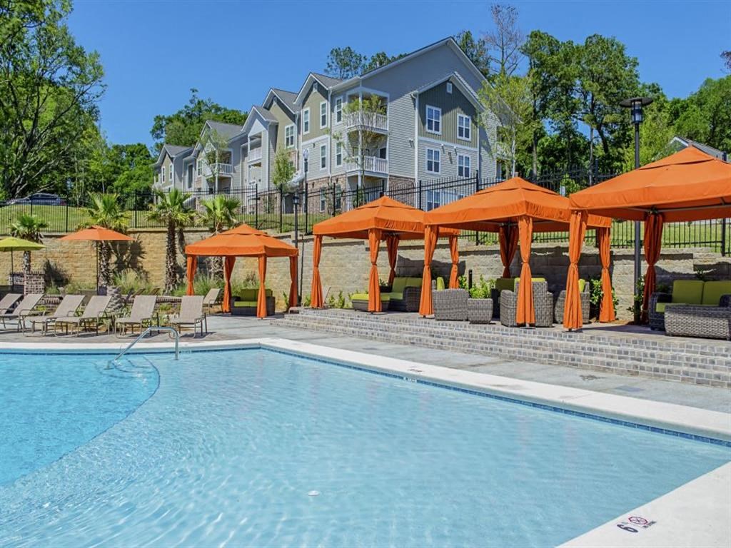 a swimming pool with orange umbrellas in front of an apartment building