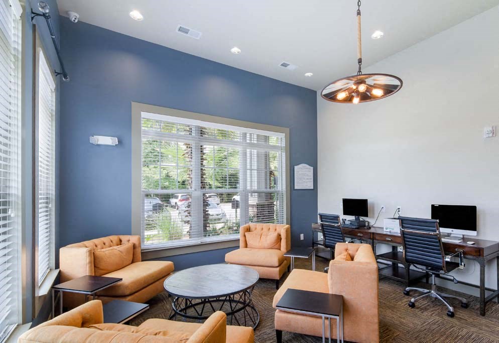 a room with couches and chairs and a table with a computer on it