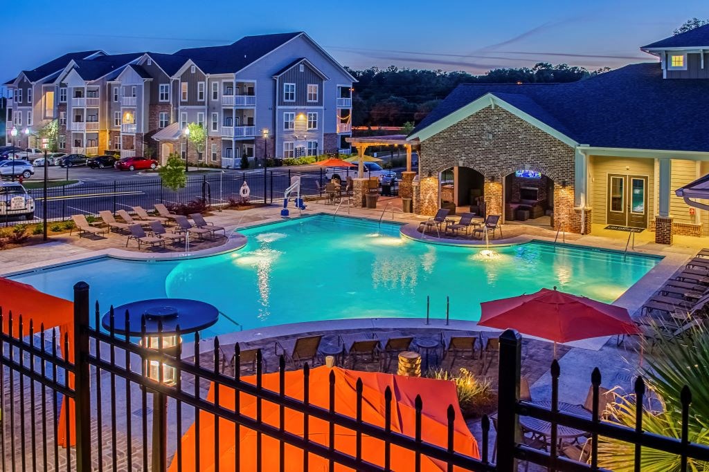 a resort style pool with lounge chairs and umbrellas at dusk