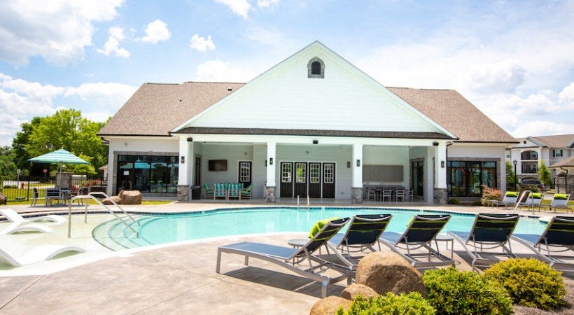 a swimming pool with lounge chairs in front of a building