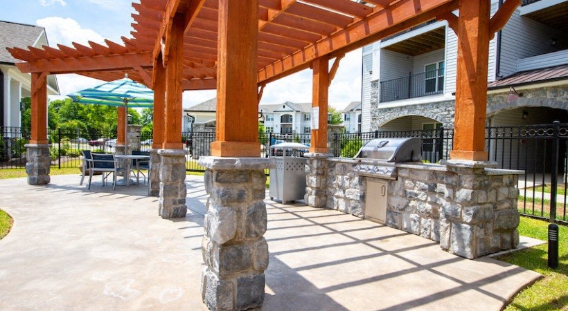 a covered patio with a grill and a table and chairs