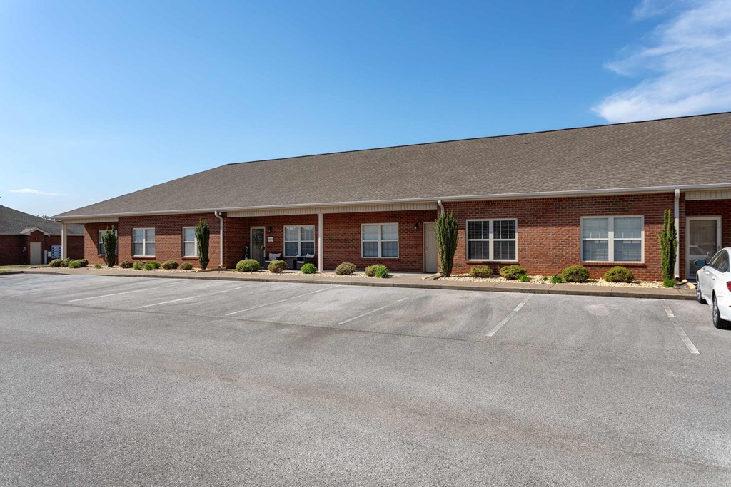 A white car is parked in front of a brick building.