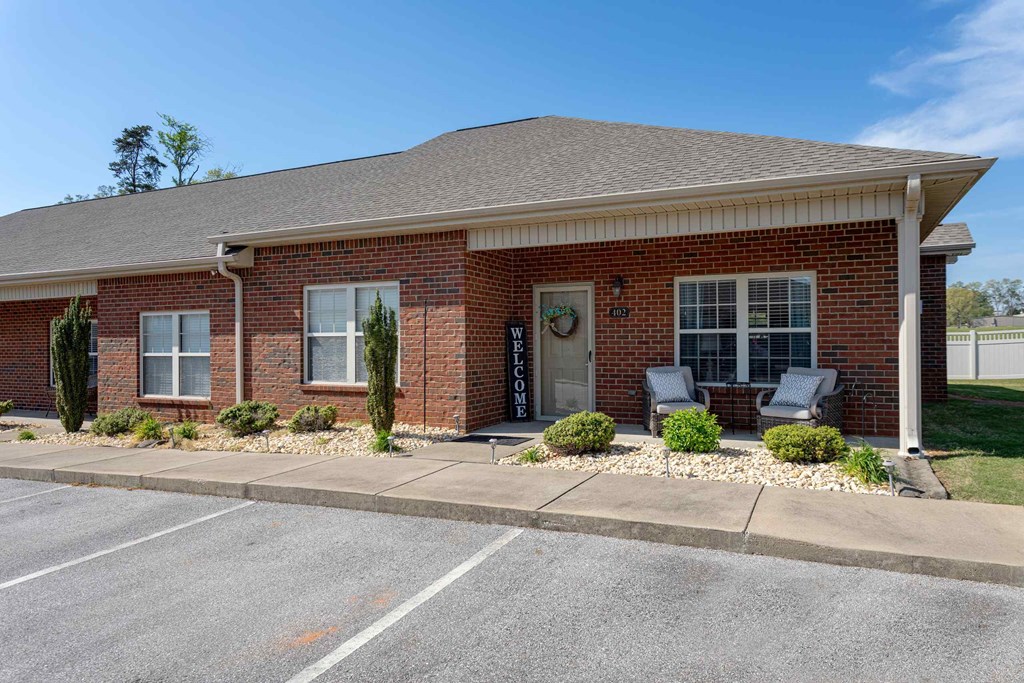 A brick apartment with a parking lot in front of it.