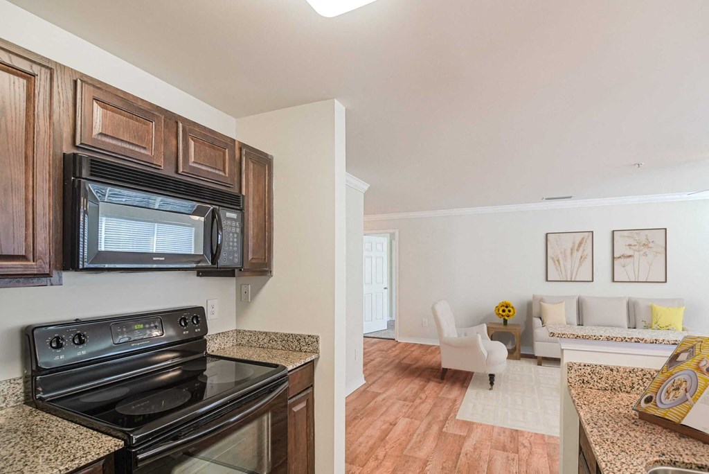 a kitchen with a stove and microwave and a living room with a couch at 10X Audubon Park apartments in Daphne, AL 