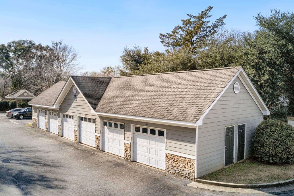 a car garage with white doors and a parking lot at 10X Audubon Park apartments in Daphne, AL 