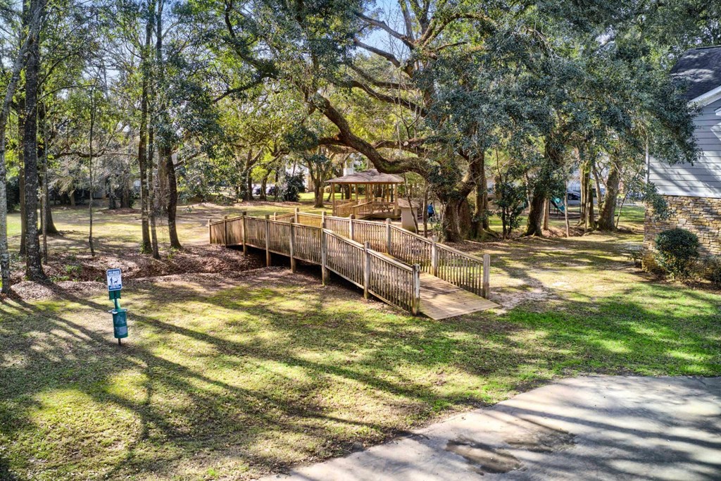a wooden bridge in a park with trees and a gazebo at 10X Audubon Park apartments in Daphne, AL 