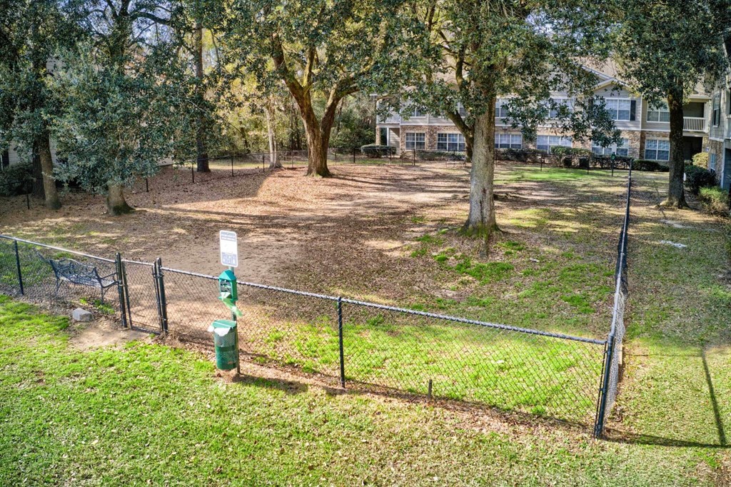 a fenced in yard with trees and houses in the background at 10X Audubon Park apartments in Daphne, AL 