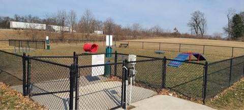 a dog park with a chain link fence and playground equipment t The Pomenade at Founders Square Apartments in Portage, IN