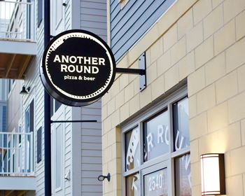 a sign for another round pizza and beer on the side of a building