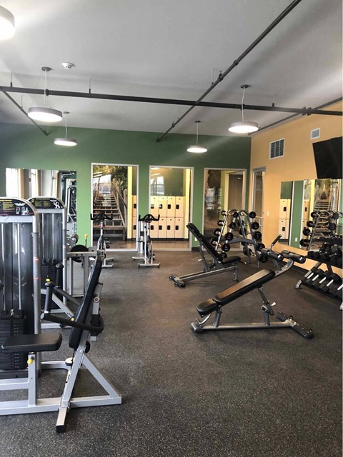 a gym with weights and other exercise equipment a game room with a pool table and chairs at The Pomenade at Founders Square Apartments in Portage, IN