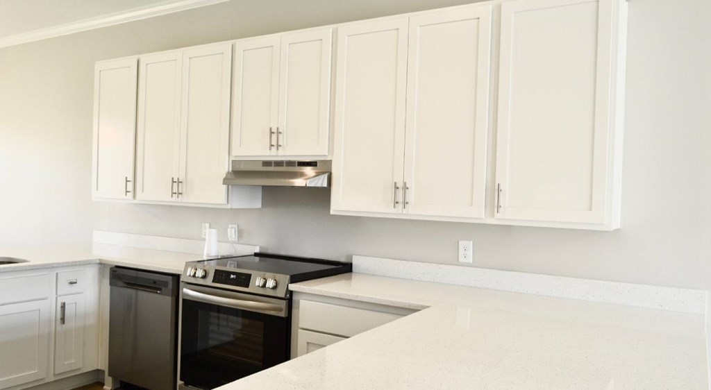 A kitchen with white cabinets and a black stove top.