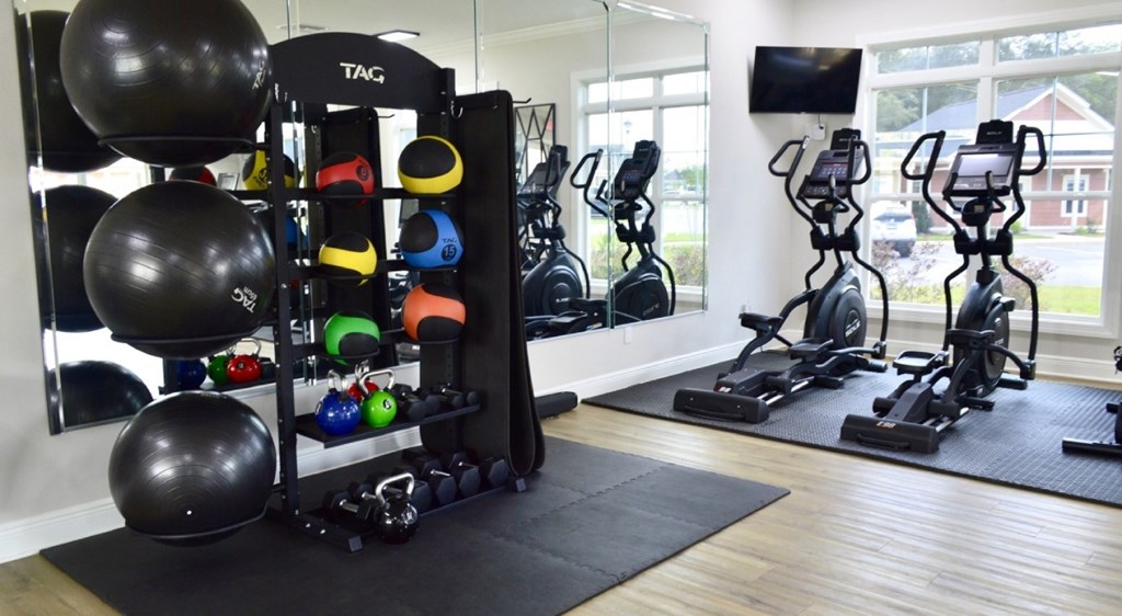 A gym room with a variety of exercise equipment including a TRX suspension trainer.