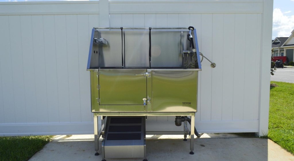 A yellow and silver portable sink with a step is placed on a concrete surface.