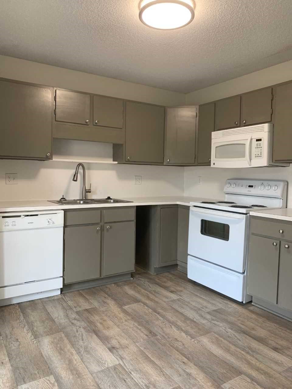 an empty kitchen with white appliances and stainless steel cabinets