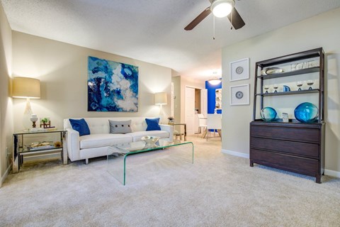 A living room with a white couch and a blue painting on the wall.