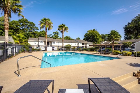 A swimming pool surrounded by palm trees and a fence.