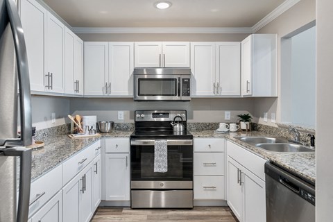 a white kitchen with stainless steel appliances and granite counter tops
