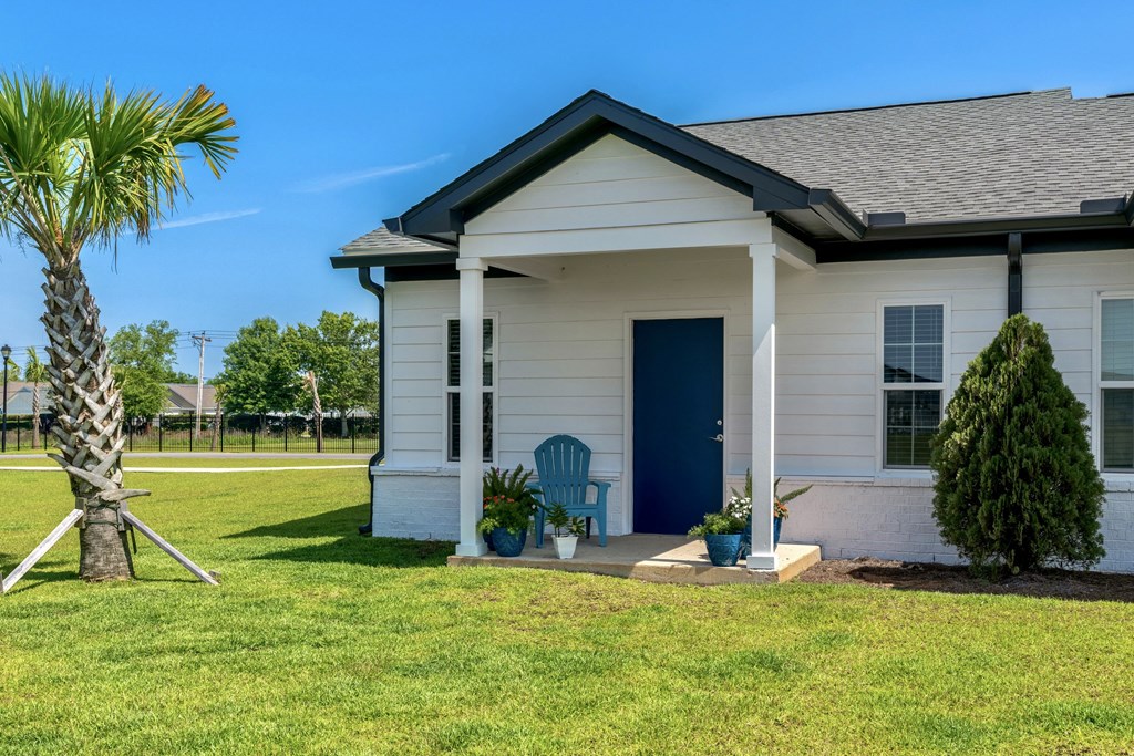 a small white house with a blue door and a palm tree in front of it