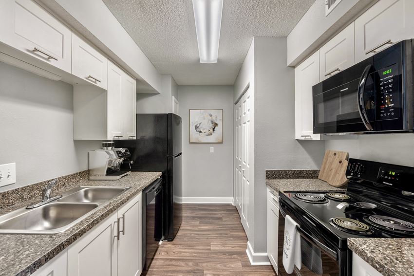 kitchen with plank flooring at Mirabelle Apartments in Mobile, Alabama a kitchen with white cabinets and black appliances at Mirabelle Apartments in Mobile, Alabama - Photo Gallery