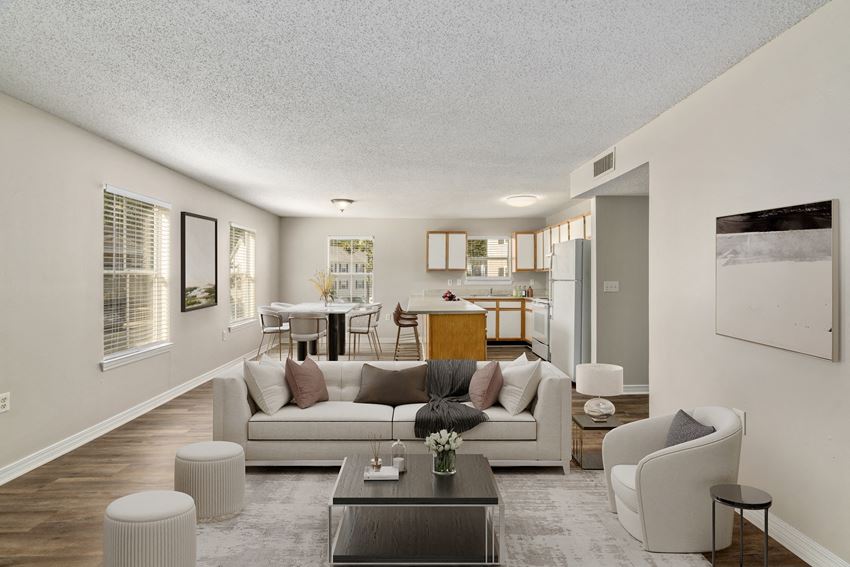 a living room with a couch table and chairs and a kitchen in the background
