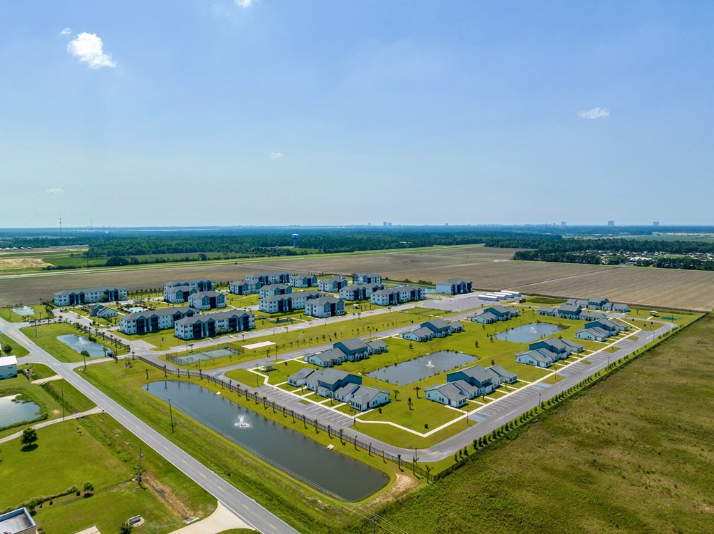 an aerial view of a housing complex in a grassy area next to a body of water