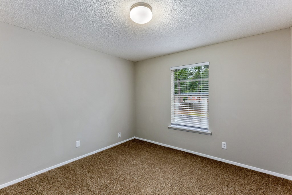 an empty bedroom with a window and a cork floor