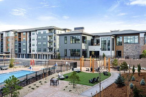 A modern apartment complex with a pool and outdoor seating area.