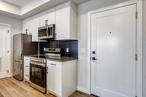 A kitchen with white cabinets and a black countertop.