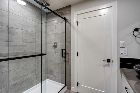 A white door is in a bathroom with a glass shower.