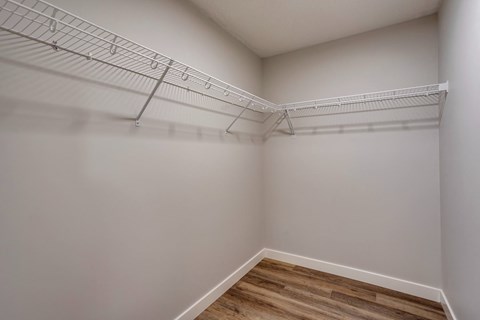 A white wall with a wooden floor and a metal rack on the wall.