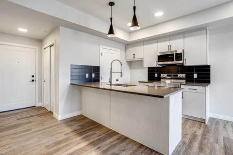 A modern kitchen with a wooden floor and white walls.