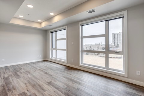 A spacious room with large windows and wooden flooring.
