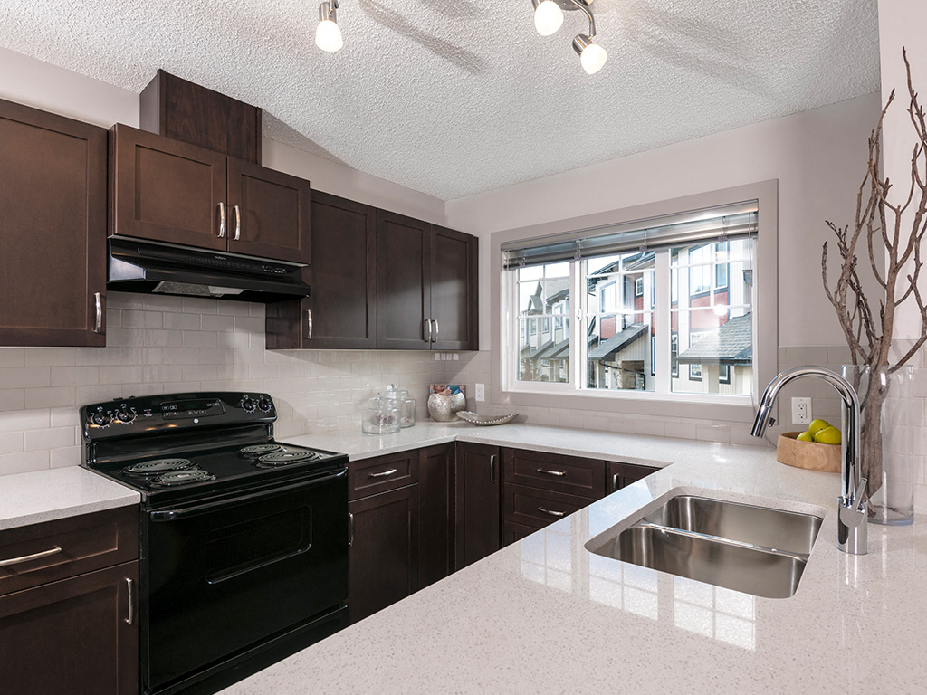 A kitchen with a black stove top oven and brown cabinets.