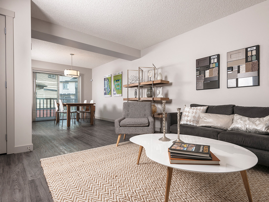 A living room with a grey couch, a white coffee table, and a grey armchair.