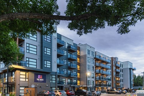 A large apartment complex with a parking lot in front.